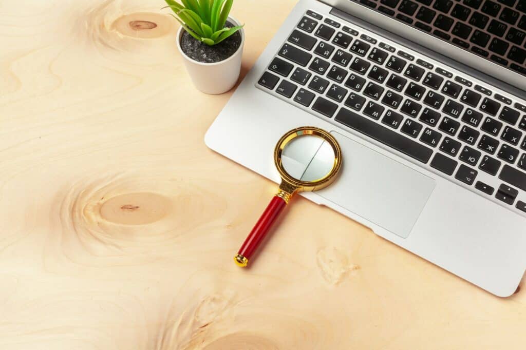 Laptop computer keyboard with magnifying glass, concept of search