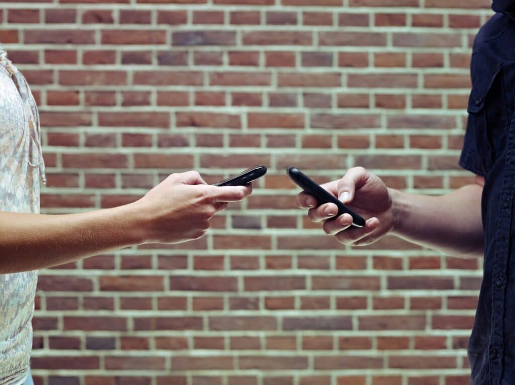 Man And Woman Using Cellphones To Share Files And Contacts