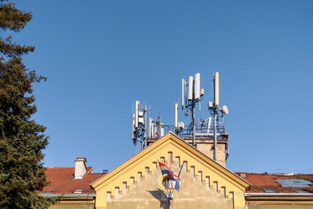 Mobile network cell tower on top of building in city.