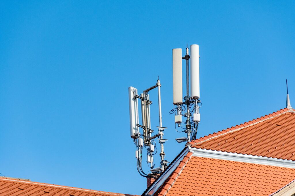 Mobile network cell tower on roof of building in city.