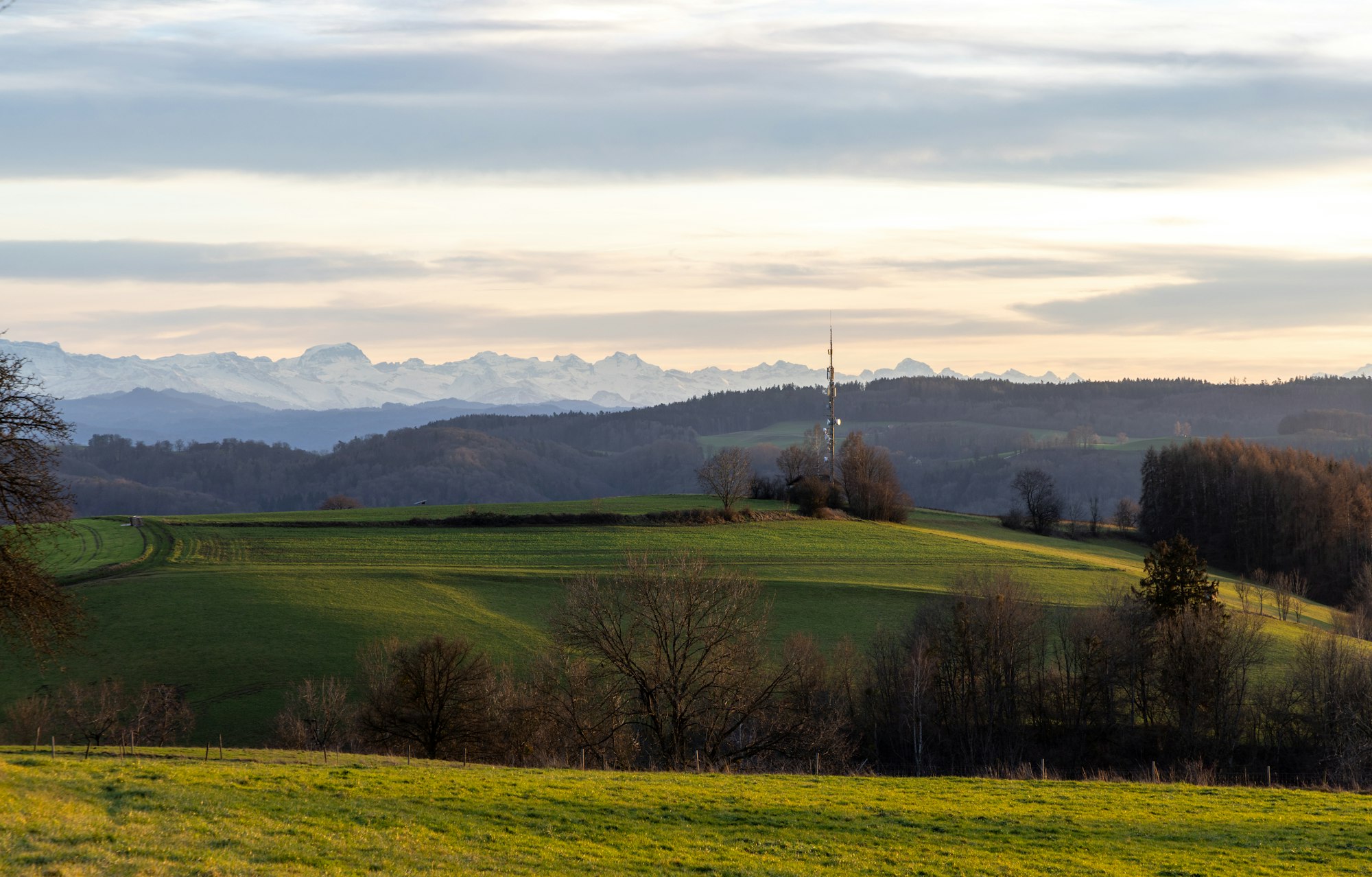 Telecom tower in hilly green valley at sunset background