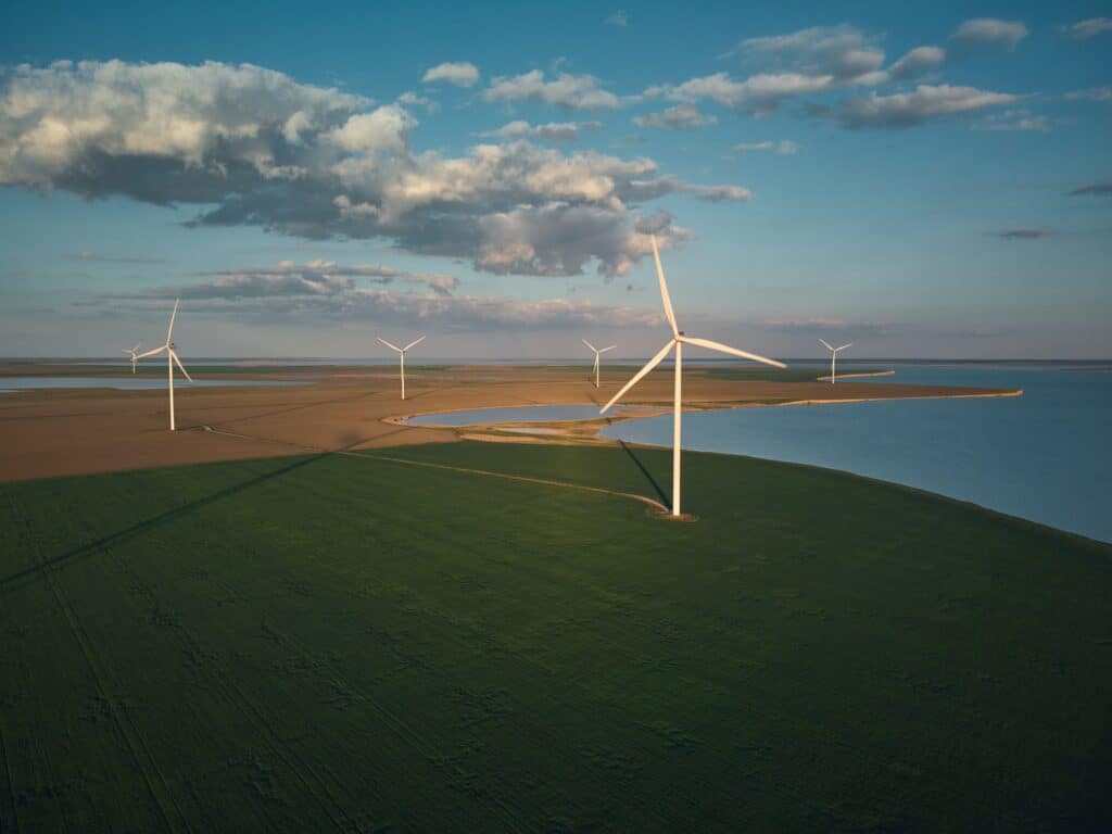 Aerial View Of Wind Turbines And Agriculture Field Near The Sea At Sunset