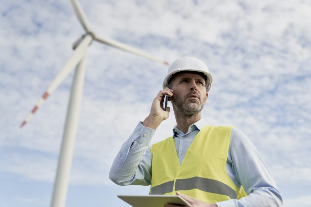 Caucasian Male Engineer Standing On Wind Turbine Field With Digital Tablet And Talking On The Phone