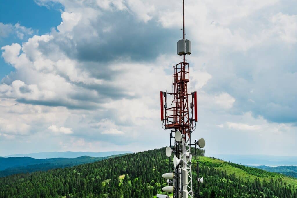 Telecommunication Transmitter Tower With Antennas Of Cellular Communication In Mountains Against Sky