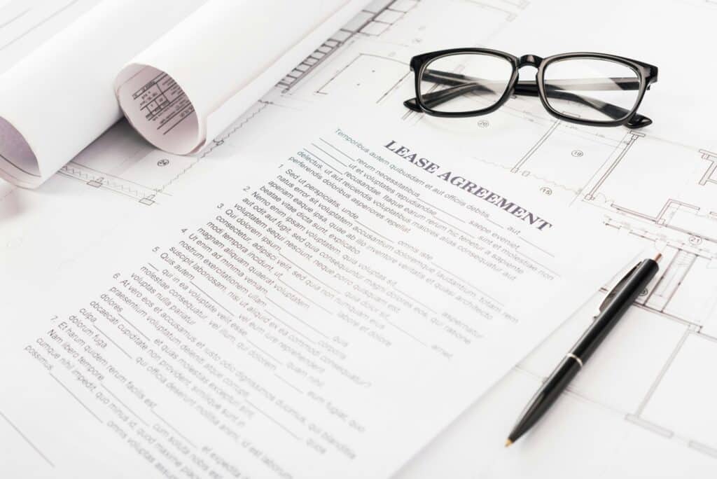 Document With Lease Agreement Lettering Near Glasses, Blueprints And Pen On Desk